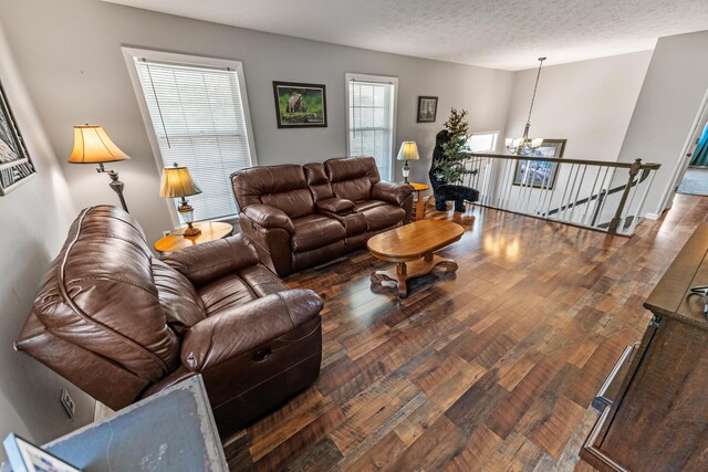 living room featuring a notable chandelier, dark hardwood / wood-style flooring, and a textured ceiling