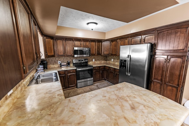 kitchen featuring appliances with stainless steel finishes, sink, backsplash, dark brown cabinetry, and a textured ceiling