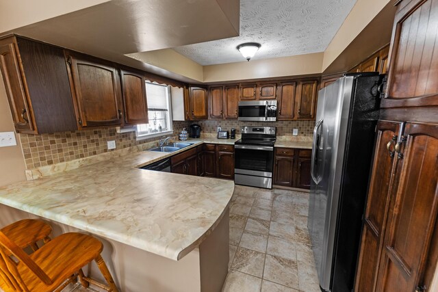 kitchen featuring light tile patterned floors, stainless steel appliances, decorative backsplash, sink, and kitchen peninsula