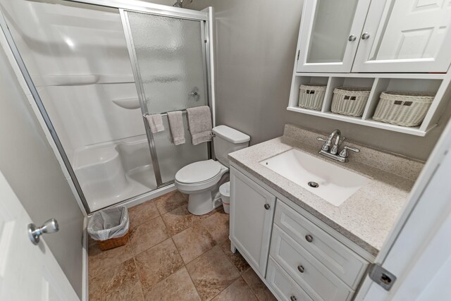 bathroom featuring a shower with door, tile patterned floors, toilet, and vanity