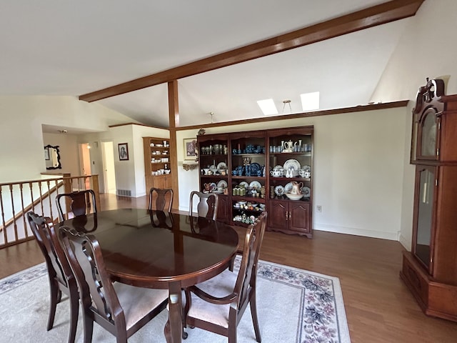 dining space with hardwood / wood-style flooring and vaulted ceiling with skylight