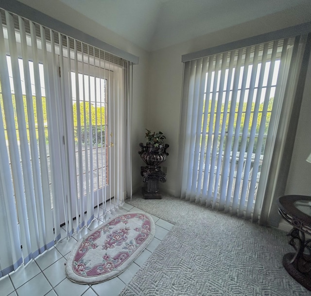 doorway to outside featuring light tile patterned flooring and lofted ceiling