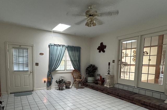 tiled foyer entrance featuring ceiling fan and a skylight