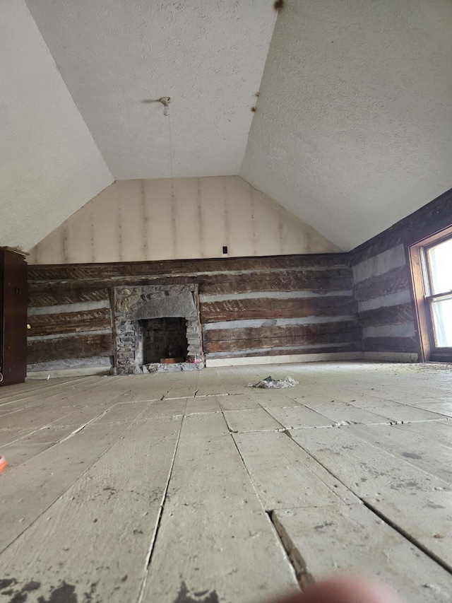 additional living space featuring lofted ceiling, a fireplace, and a textured ceiling