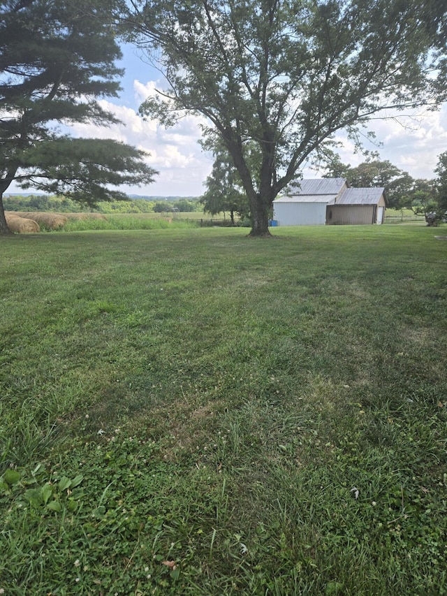 view of yard featuring a rural view, an outbuilding, and an outdoor structure