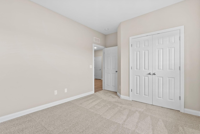 unfurnished bedroom with light colored carpet and a closet