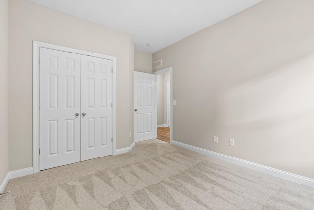 unfurnished bedroom with light colored carpet and a closet