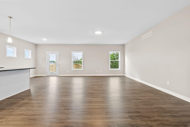 unfurnished living room with a healthy amount of sunlight and dark wood-type flooring