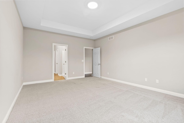 empty room with a raised ceiling and carpet floors