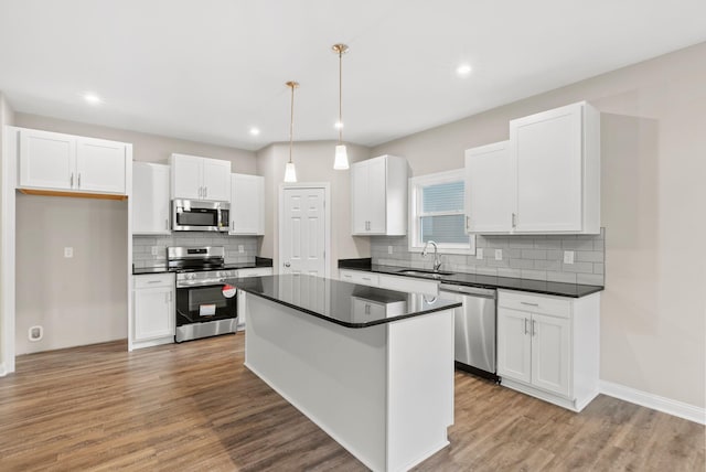 kitchen with white cabinets, stainless steel appliances, a center island, and hanging light fixtures