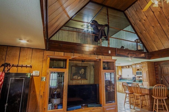 kitchen featuring lofted ceiling, a kitchen bar, wood walls, and wooden ceiling