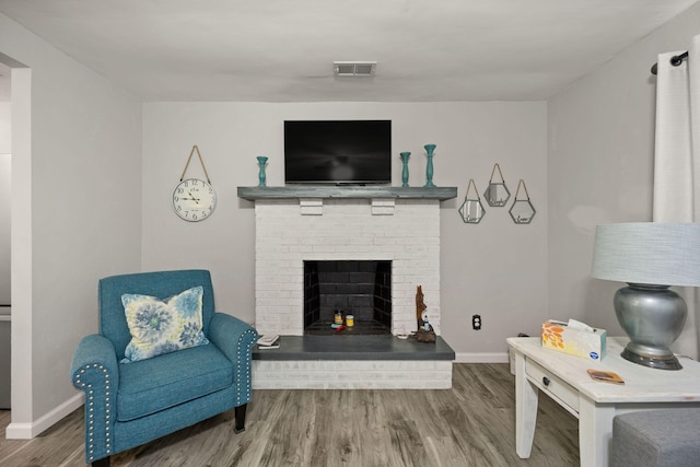 living room with hardwood / wood-style flooring and a brick fireplace