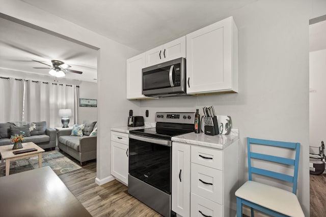 kitchen with dark hardwood / wood-style flooring, ceiling fan, white cabinets, and appliances with stainless steel finishes