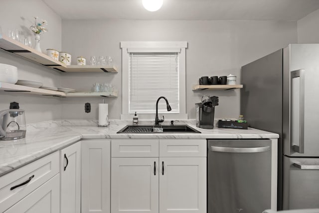 kitchen featuring light stone counters, appliances with stainless steel finishes, sink, and white cabinets