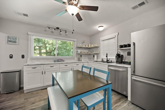 kitchen featuring stainless steel appliances, white cabinetry, sink, and light hardwood / wood-style flooring