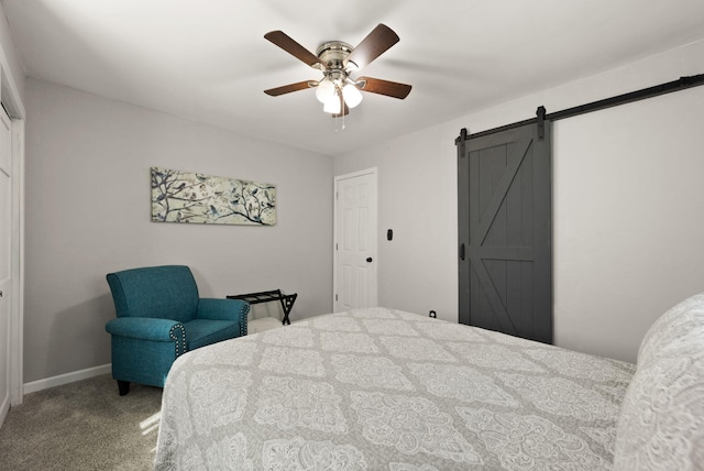 bedroom featuring a barn door, ceiling fan, and carpet