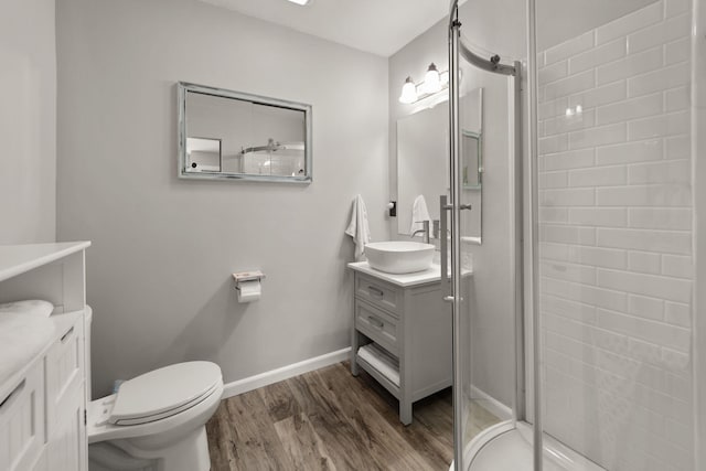 bathroom featuring hardwood / wood-style flooring, vanity, toilet, and a shower with door