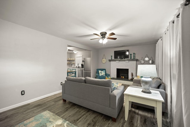 living room featuring ceiling fan, a fireplace, dark hardwood / wood-style floors, and sink