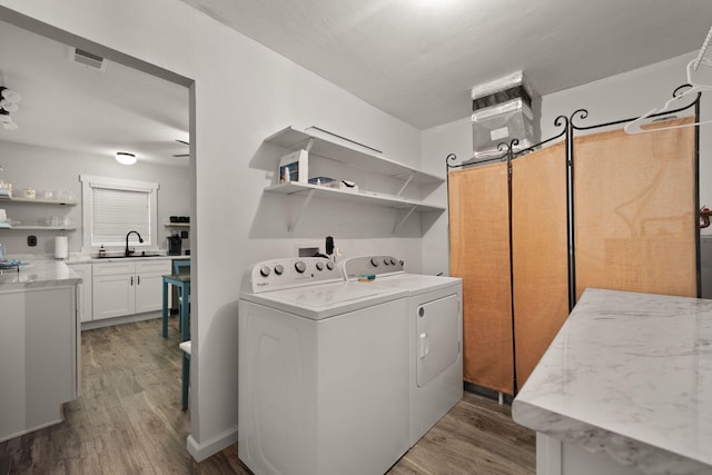 washroom featuring sink, washing machine and dryer, and hardwood / wood-style floors