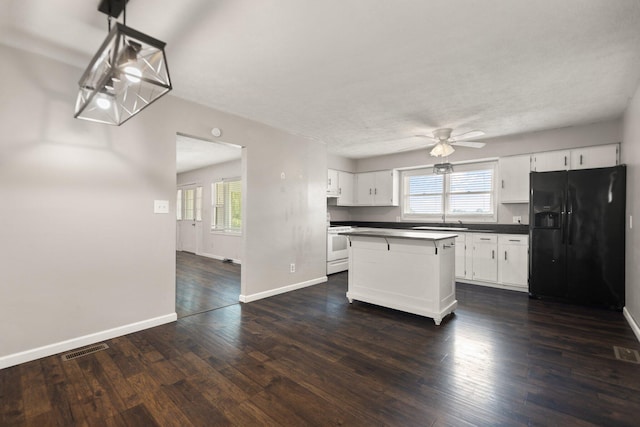 kitchen featuring a center island, dark countertops, black refrigerator with ice dispenser, white cabinets, and white stove