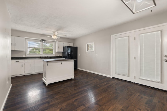 kitchen featuring dark countertops, a center island, and white cabinets