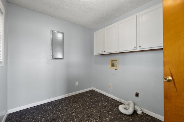 clothes washing area with cabinet space, a textured ceiling, baseboards, and hookup for an electric dryer