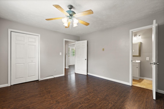 unfurnished bedroom with ceiling fan, dark wood-type flooring, a closet, and baseboards