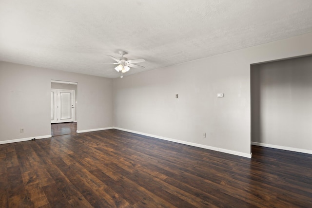 spare room featuring dark wood-type flooring, a textured ceiling, baseboards, and a ceiling fan