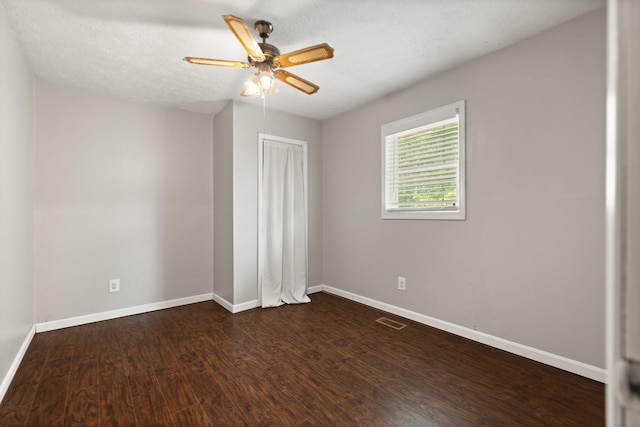 spare room with dark wood-style flooring, visible vents, a ceiling fan, a textured ceiling, and baseboards