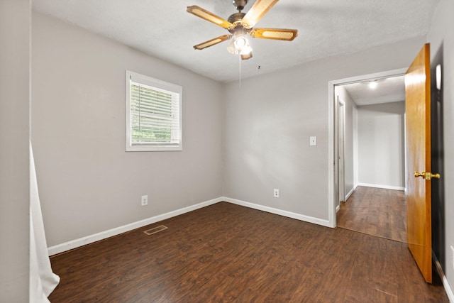 spare room featuring ceiling fan, a textured ceiling, visible vents, baseboards, and dark wood-style floors