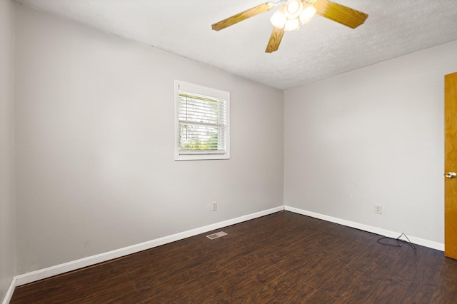 empty room with a textured ceiling, dark wood-type flooring, visible vents, a ceiling fan, and baseboards