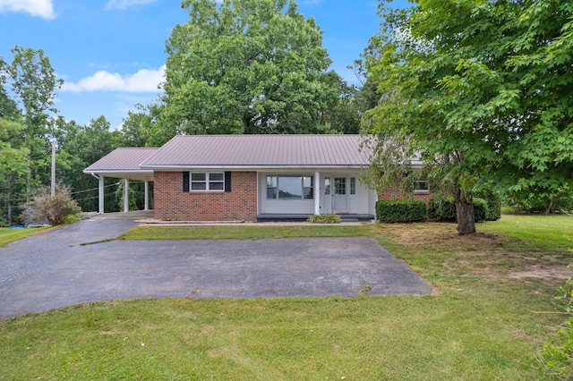 ranch-style home with metal roof, brick siding, driveway, a carport, and a front yard