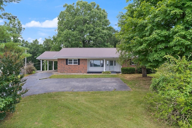 ranch-style house featuring metal roof, driveway, a carport, and a front yard