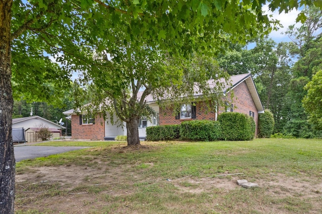 view of front of property featuring aphalt driveway, a front yard, and brick siding