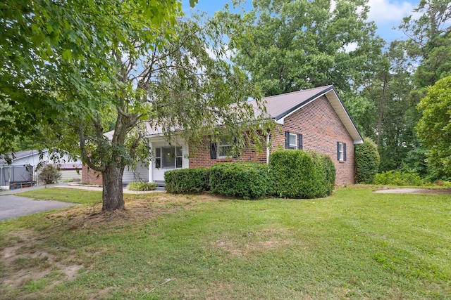 view of front of home with aphalt driveway, a front yard, brick siding, and a garage