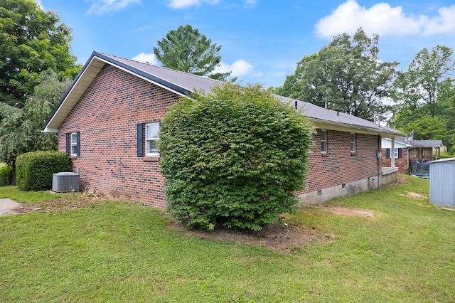 view of side of home featuring brick siding, crawl space, cooling unit, and a lawn