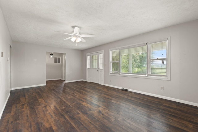 empty room with dark wood-type flooring, ceiling fan, a textured ceiling, and baseboards