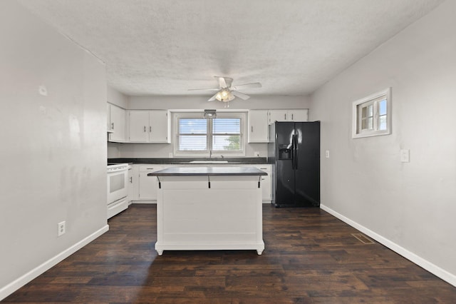 kitchen featuring dark countertops, white cabinets, white range with electric cooktop, and black fridge