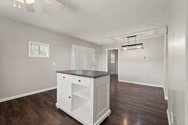 kitchen with dark wood finished floors, white cabinets, dark countertops, hanging light fixtures, and open shelves