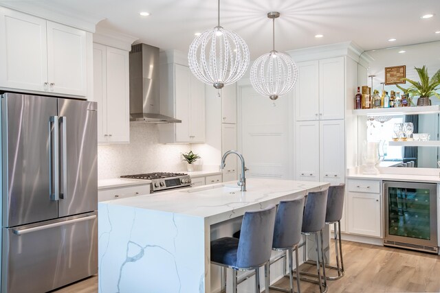 kitchen featuring light hardwood / wood-style flooring, wall chimney range hood, beverage cooler, stainless steel appliances, and sink