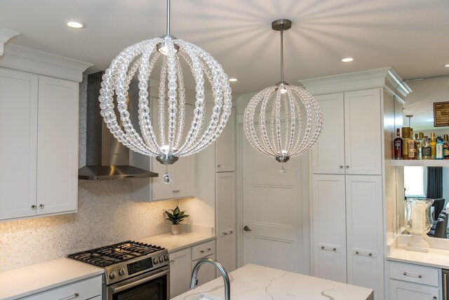 kitchen featuring white cabinets, wall chimney range hood, hanging light fixtures, decorative backsplash, and high end range