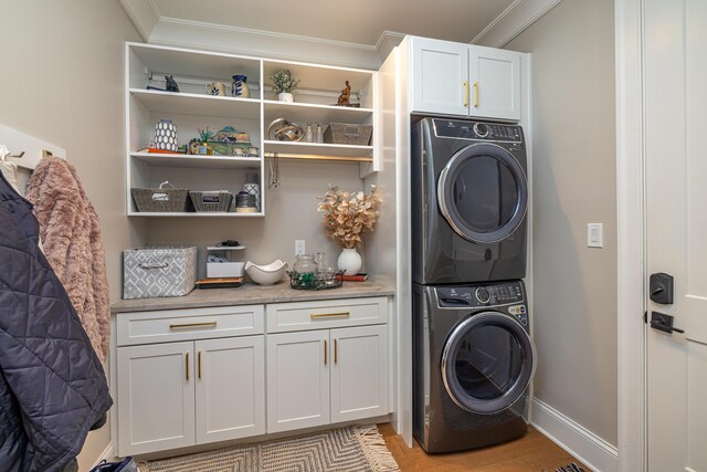 clothes washing area featuring stacked washer and dryer, cabinets, crown molding, and light hardwood / wood-style floors