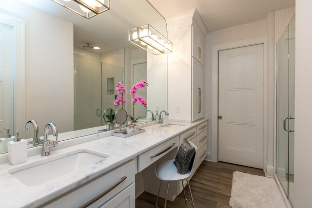 bathroom featuring a shower with shower door, wood-type flooring, and dual bowl vanity