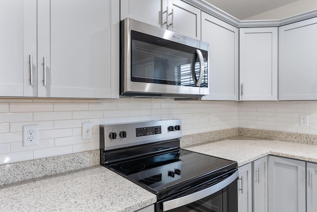 kitchen featuring stainless steel appliances, decorative backsplash, and light stone countertops