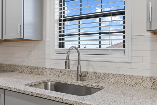 details with sink, tasteful backsplash, and light stone counters