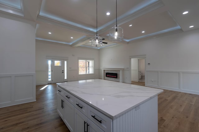 kitchen featuring hanging light fixtures, white cabinetry, light stone countertops, light hardwood / wood-style floors, and crown molding