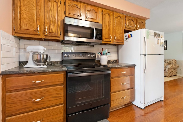 kitchen featuring electric range, white fridge, backsplash, and light wood-type flooring