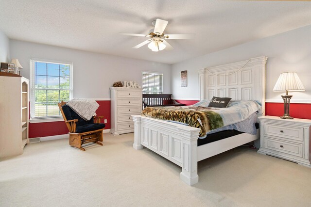 bedroom with a textured ceiling, light colored carpet, and ceiling fan