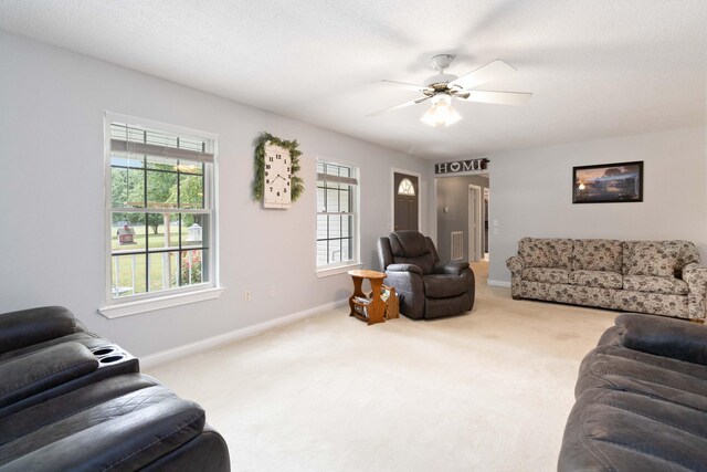 living room with a textured ceiling, ceiling fan, and carpet flooring