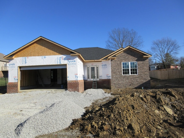 view of front of house featuring a garage, french doors, brick siding, and gravel driveway